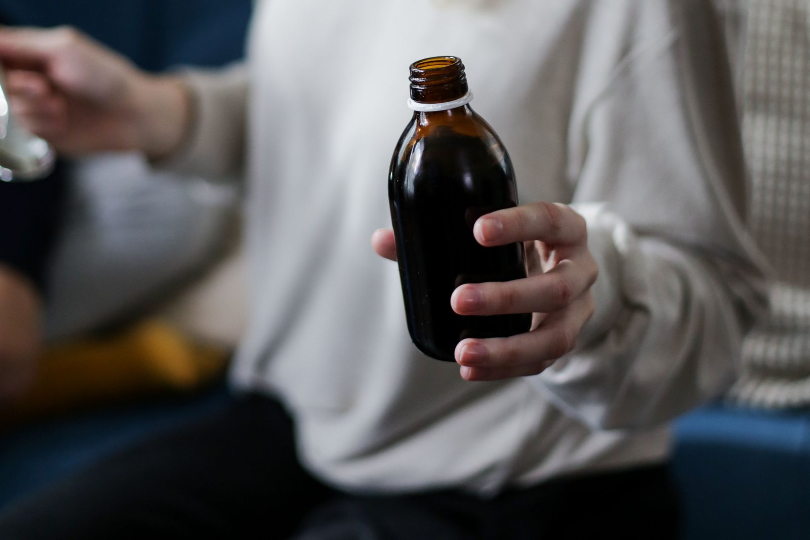 A person holding a bottle of liquid medicine