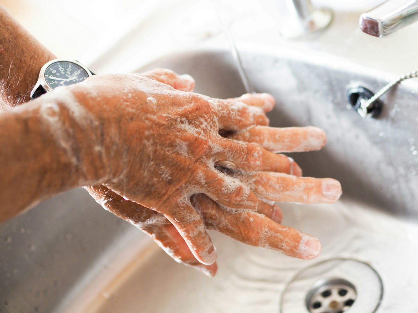 Soapy hands being washed under running water