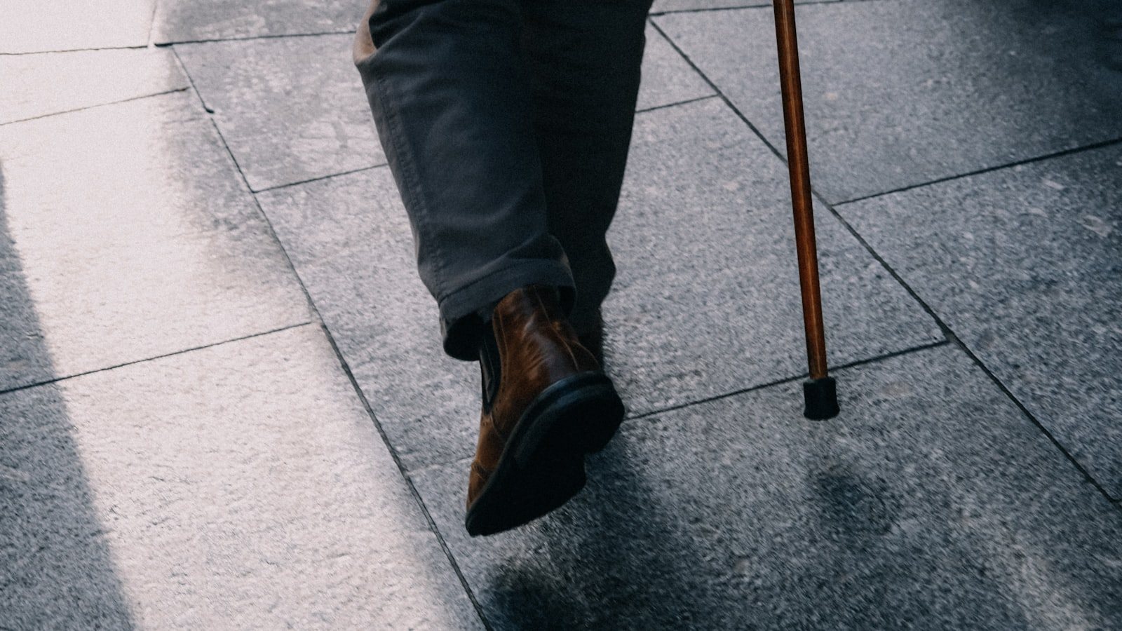 A person walking with a cane on a sidewalk