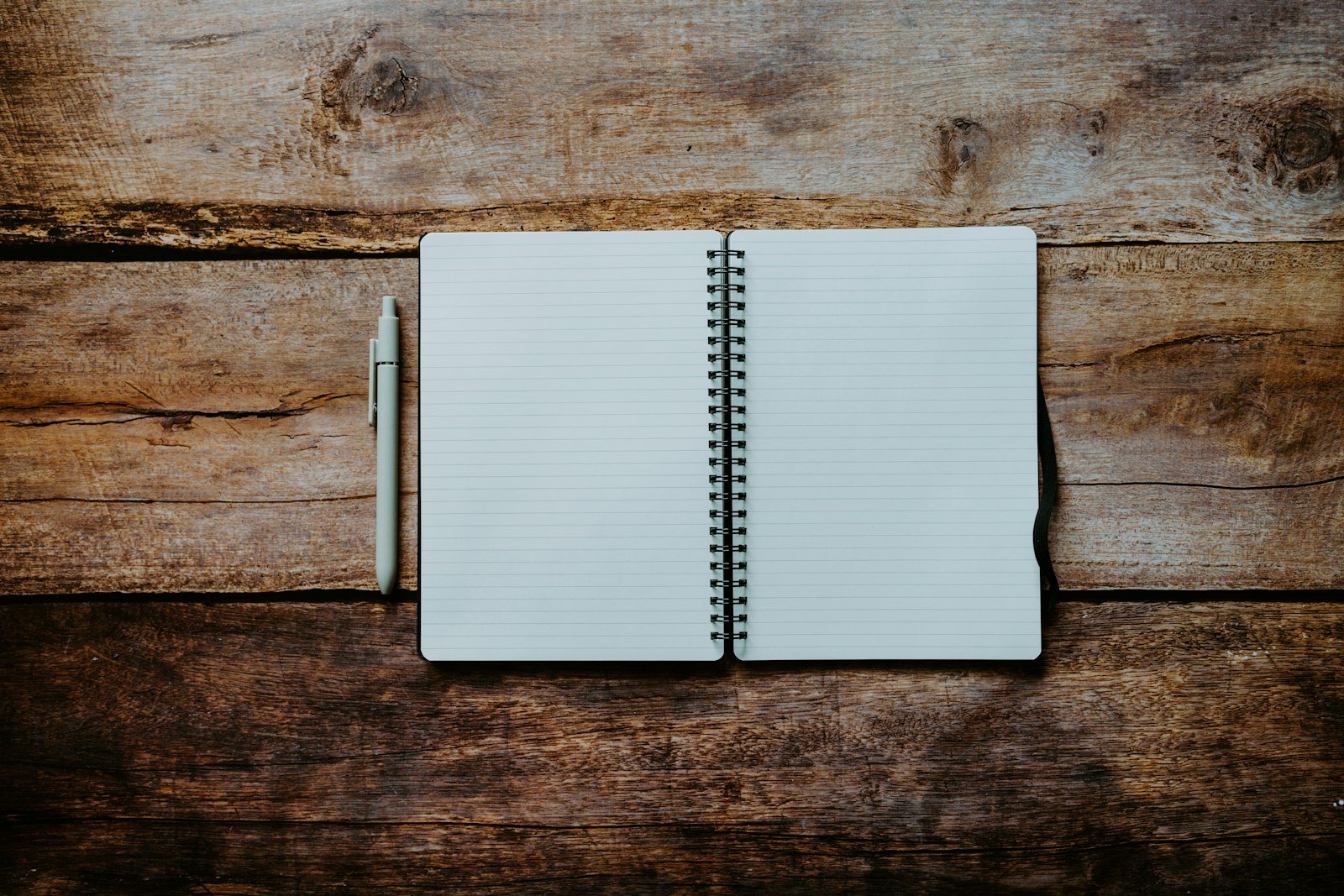 An open notebook with a pen on a wooden table